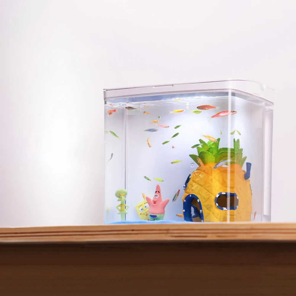 Small aquarium with cartoon characters and a pineapple-shaped hiding spot on a wooden surface.