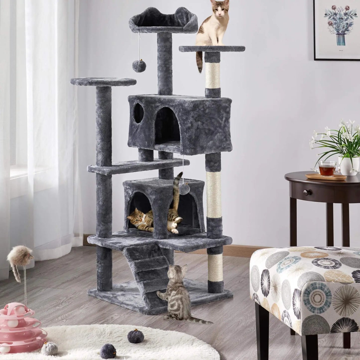 Cat tree with multiple levels and a cat sitting on top in a room setting.
