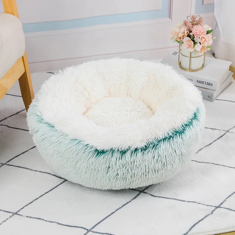 Round fluffy pet bed with white top and green base on a checkered floor.