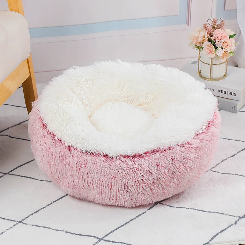Round, plush pet bed with white top and pink base on a checkered floor.